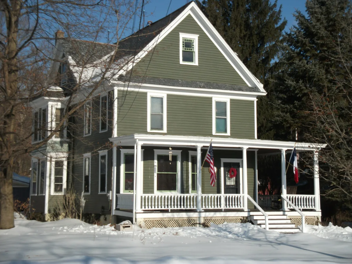 Victorian house with a wraparound porch in snow in Branchville, New Jersey