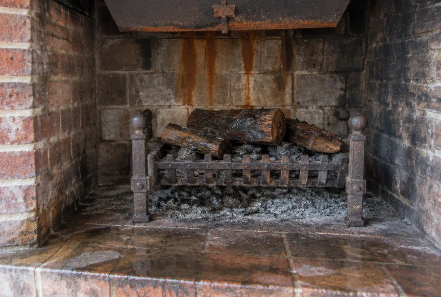 Rust streaks and a puddle of water in a brick fireplace after rain